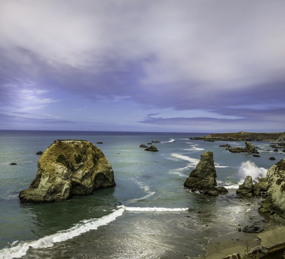 brown rock formation on sea shore under cloudy sky during daytime