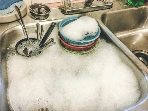 stainless steel spoons on white ceramic sink