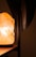 The image features a warmly lit Himalayan salt lamp on a wooden surface, casting a soft glow. The background is out of focus, with a dark vertical element partially visible to the right.