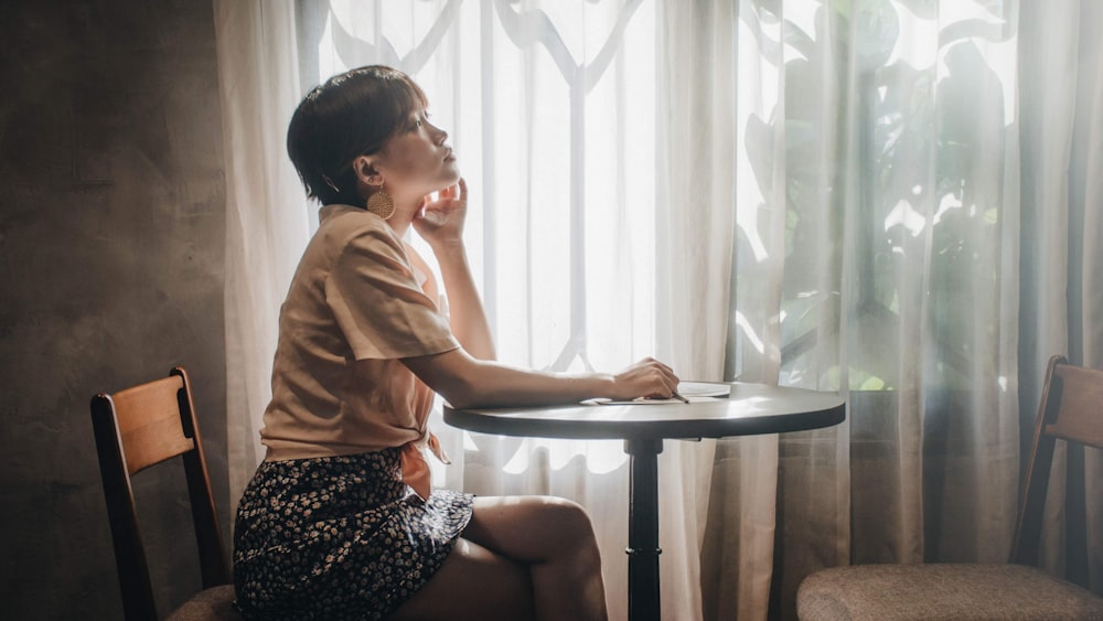 woman in brown long sleeve shirt and black and white skirt sitting on brown wooden chair