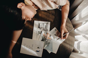 The designer sketching intricate patterns on a large drafting table in a sunlit studio.