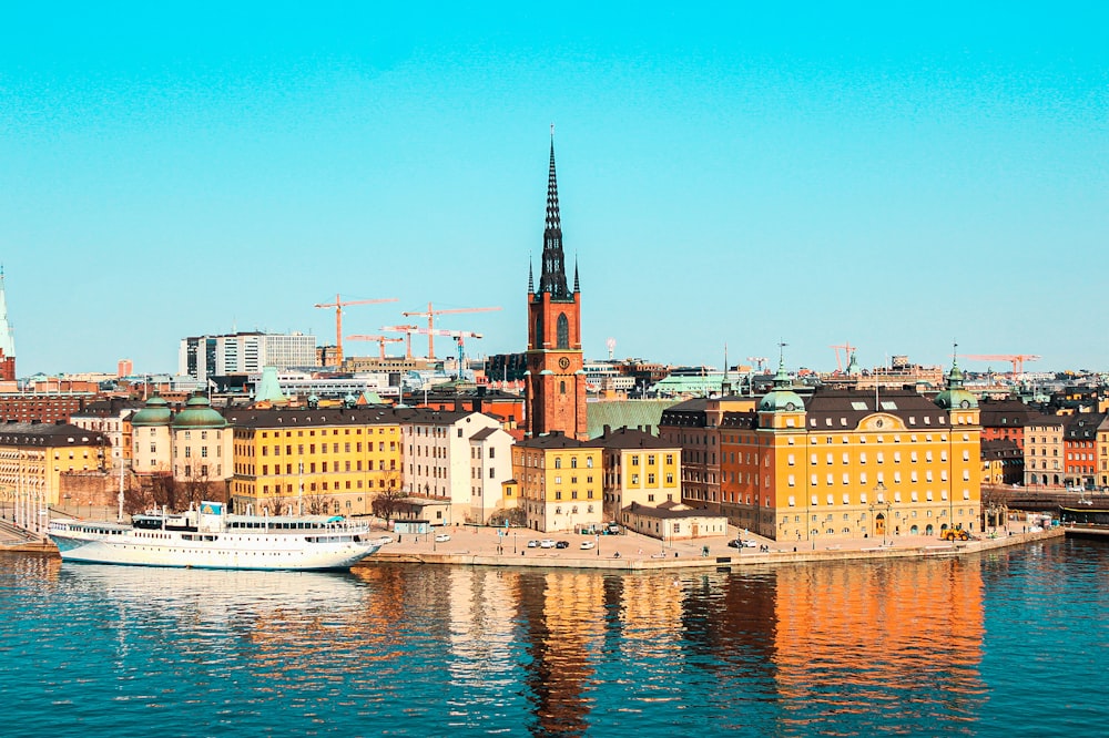 white boat on water near city buildings during daytime