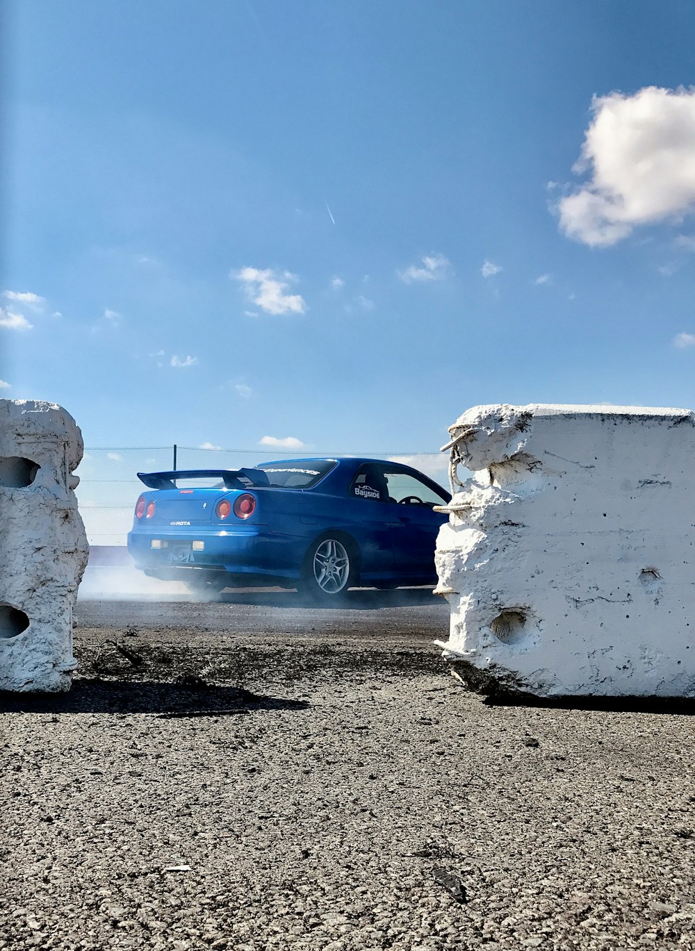 blue chevrolet car parked beside white wall