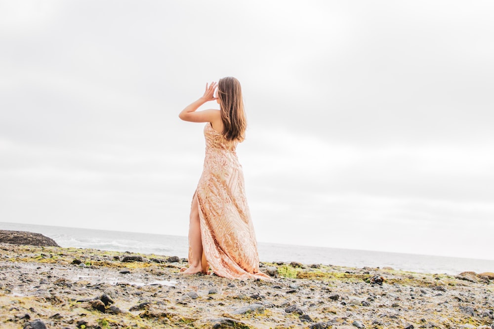 woman in yellow dress standing on beach shore during daytime