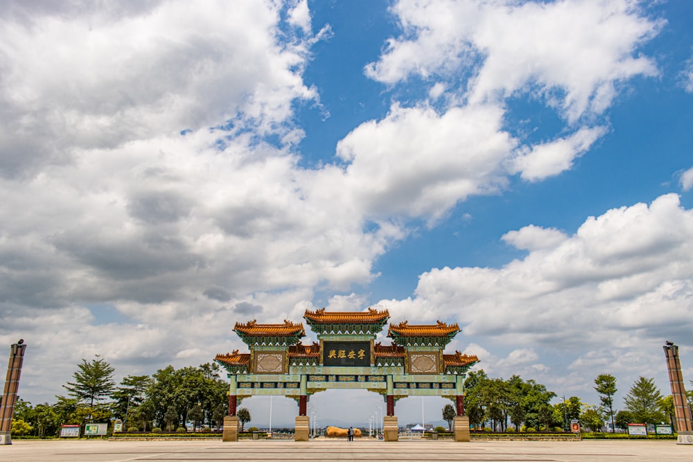 green trees near brown and white concrete building under blue and white cloudy sky during daytime