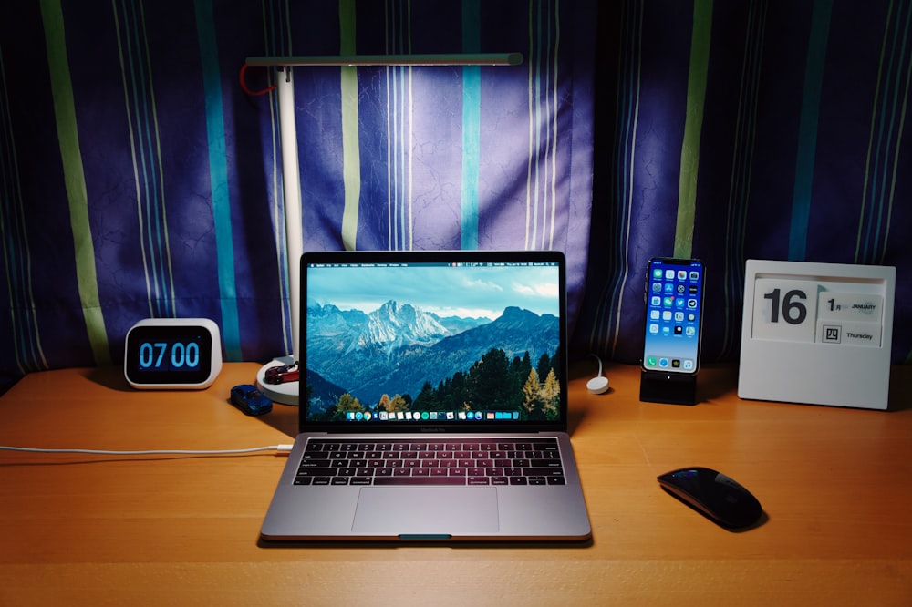 macbook pro beside black iphone 4 on brown wooden table