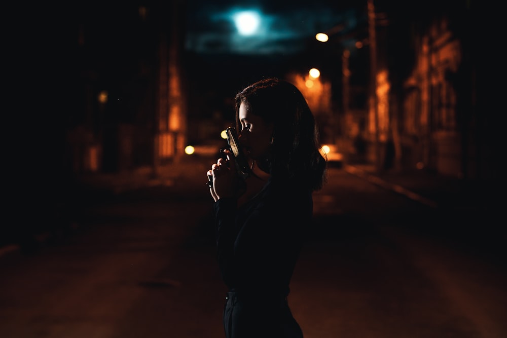 Frau in schwarzer Lederjacke steht nachts auf der Straße