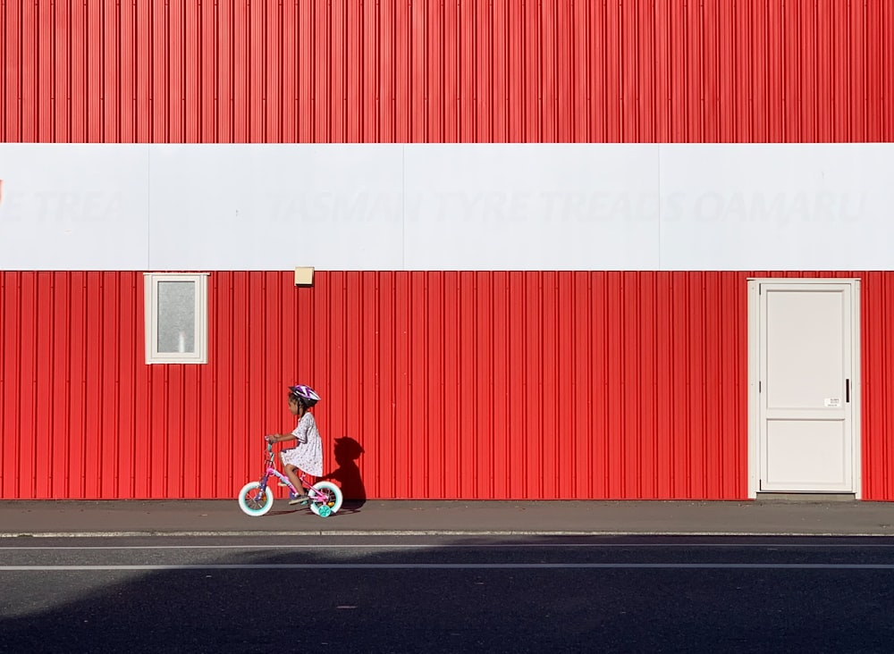 Frau in rotem Kleid fährt auf rot-weißem Fahrrad