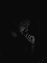 A person sitting in darkness with glowing thoughts around their head against a dark green background in a premium psychological style.
