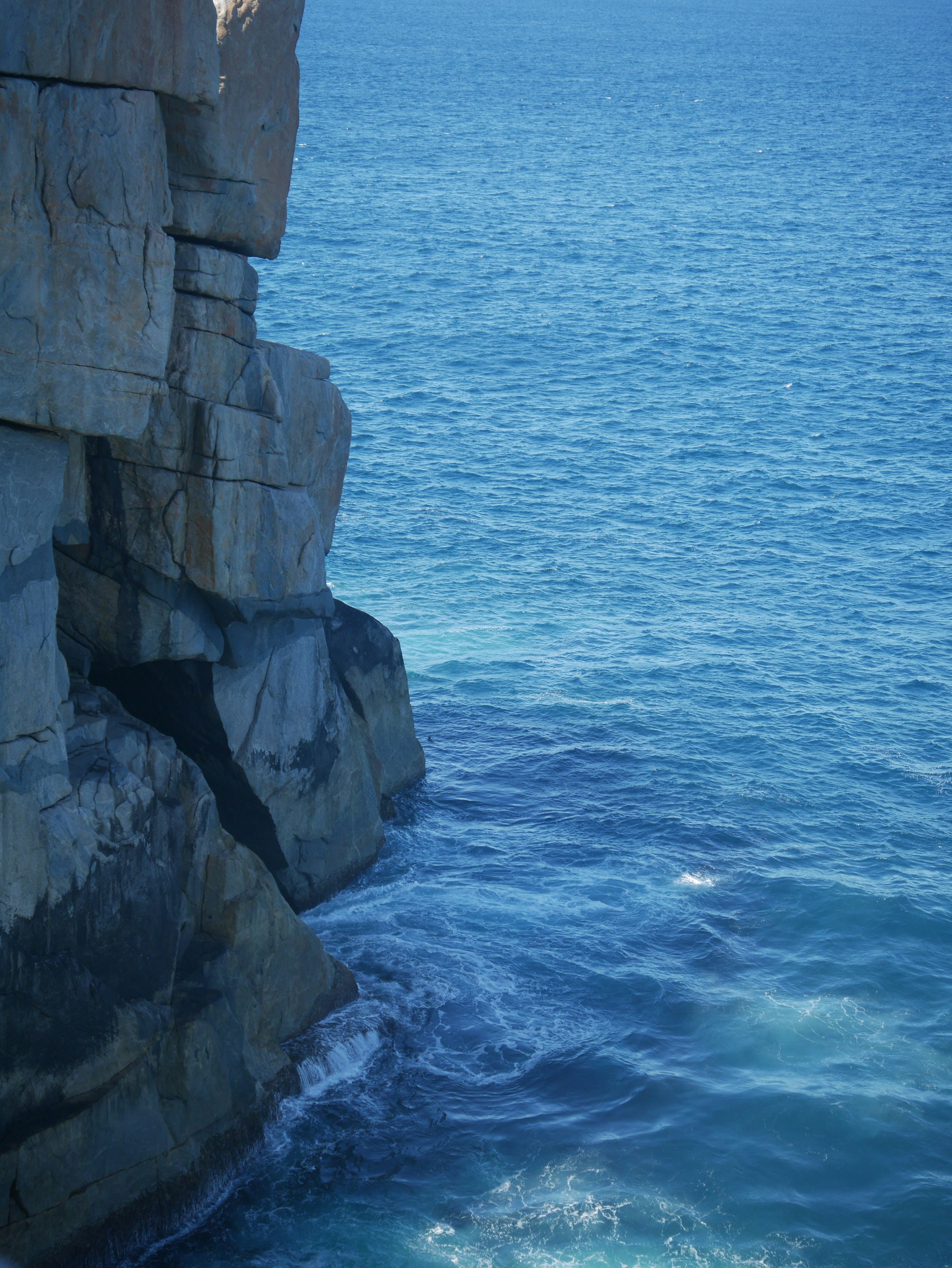 gray rock formation beside body of water during daytime