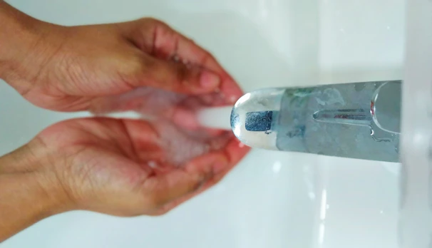Close-up of clear water flowing from a newly installed tap with hands cupping the water
