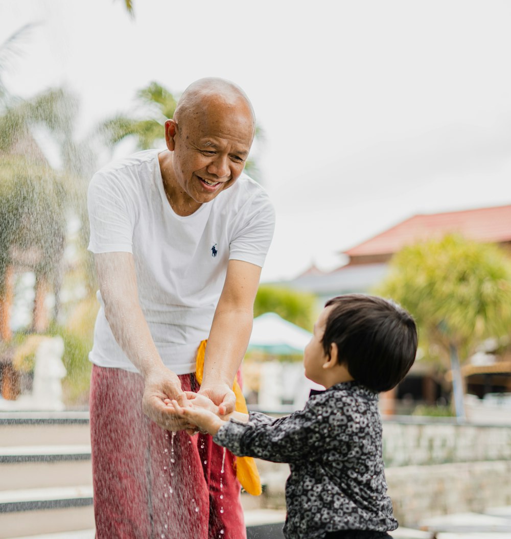 man in white crew neck t-shirt and black and white floral pants holding girl in in near on on