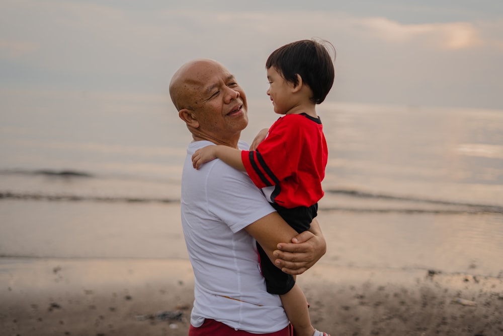 man in white and red polo shirt carrying boy in white and red shirt
