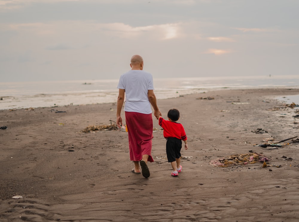 man in white t-shirt and red shorts walking on beach during daytime