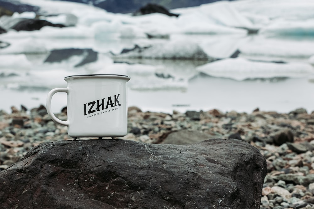 white ceramic mug on rocky shore during daytime