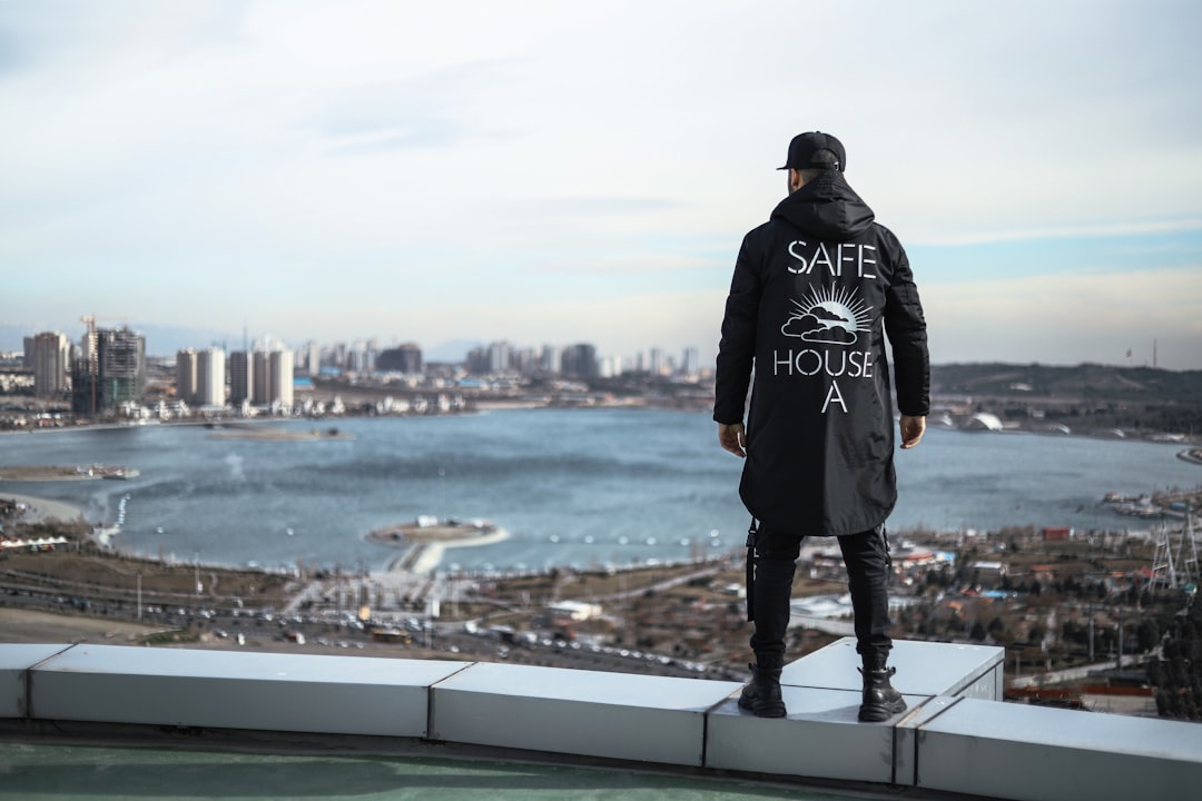 man in black jacket standing on gray metal railings during daytime