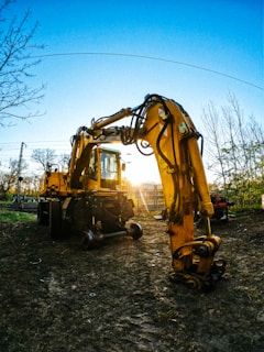 A heavy-duty excavator digging earth on a construction site during sunset.