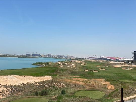green grass field near body of water during daytime in Yas Links United Arab Emirates