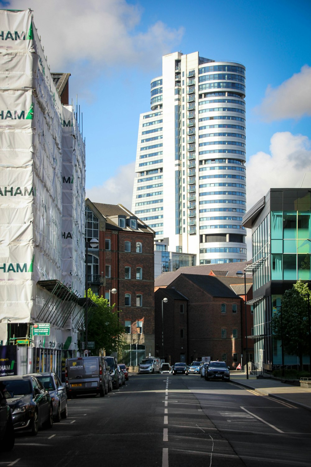 cars parked on side of the road near high rise buildings during daytime