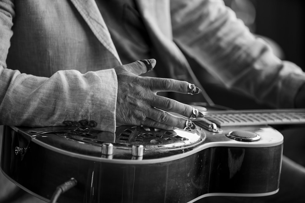 person playing guitar in grayscale photography