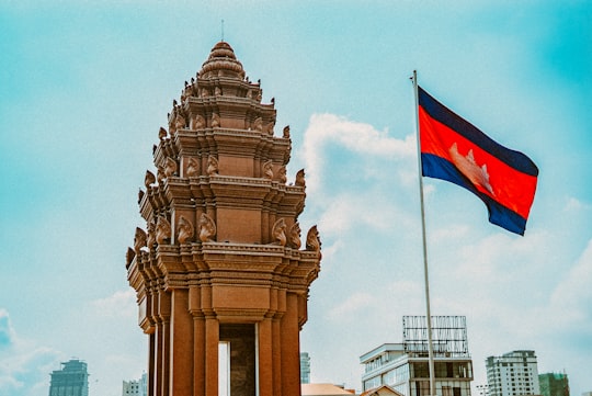 brown concrete building with flag of us a during daytime in Independence Monument Cambodia
