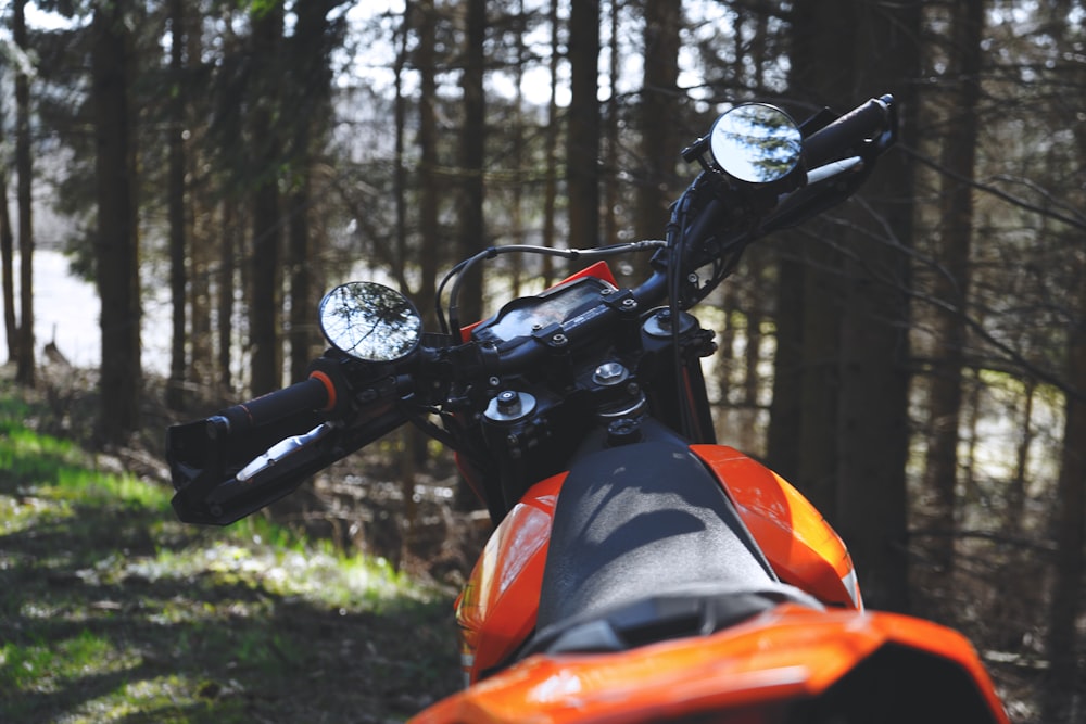 orange and black motorcycle parked on green grass field during daytime