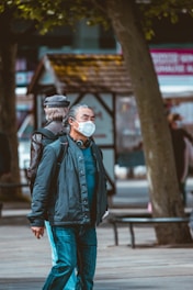 A person wearing a portable air quality monitor while walking in a city park.