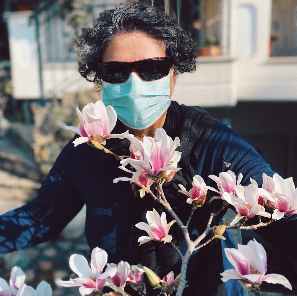 woman in blue long sleeve shirt holding white and pink flowers