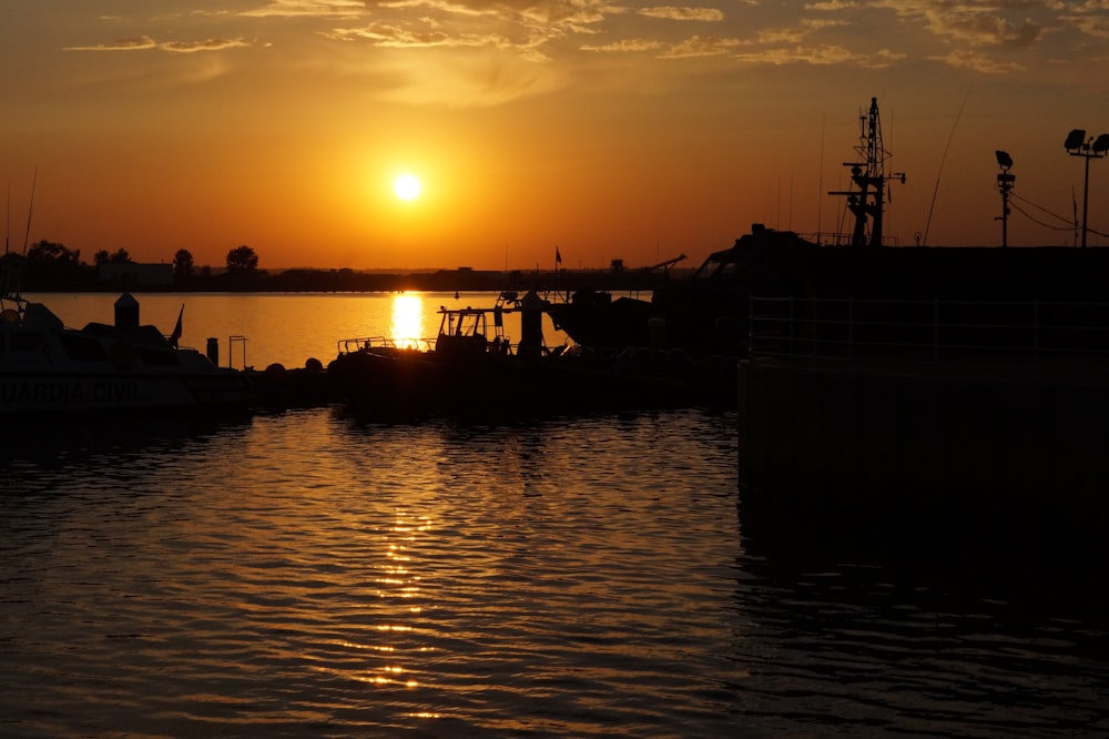 silhouette of boat on water during sunset