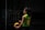 A person wearing a green and yellow sports jersey with the name and number 'Jurado 10' is standing outdoors holding a blue and yellow volleyball. The setting appears to be shadowy, possibly a sports court or outdoor area with railings visible in the background.