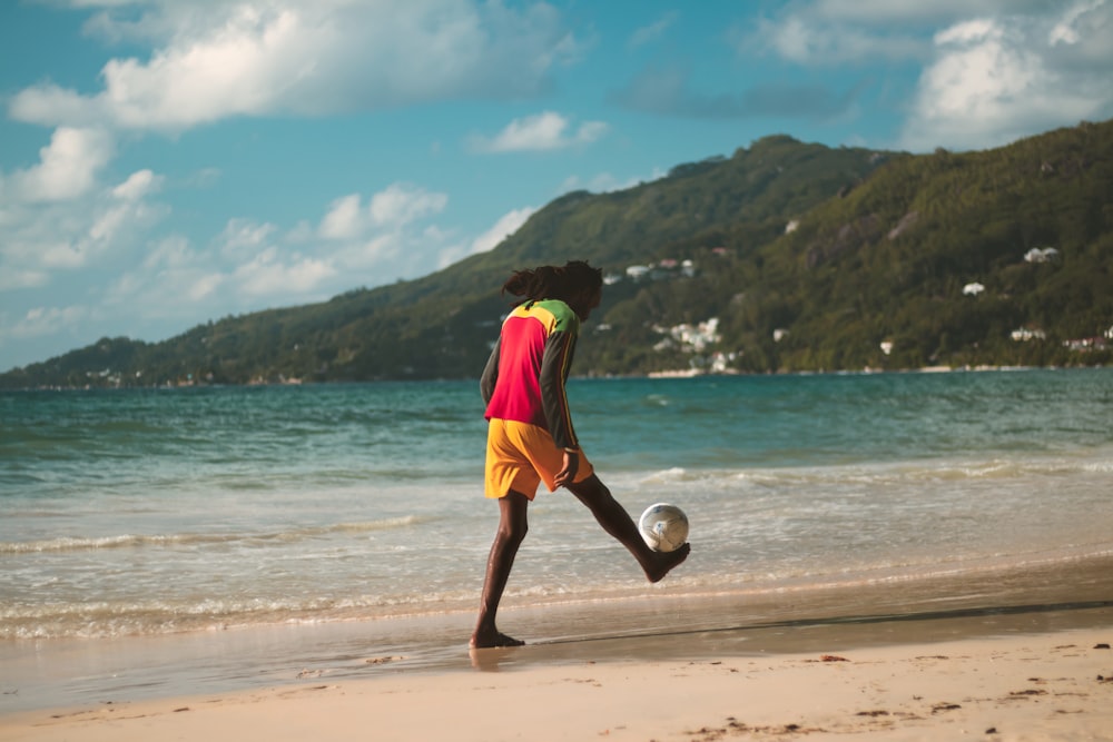 woman in purple shirt and yellow shorts running on beach during daytime