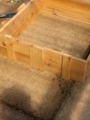 Close-up of hands assembling a sturdy wooden planter box with visible grain and clean cuts.