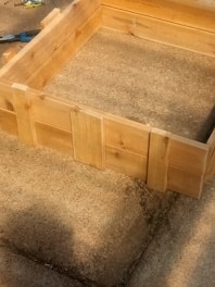 A neat wooden planter box sitting on a sunny porch, freshly built and sanded smooth.