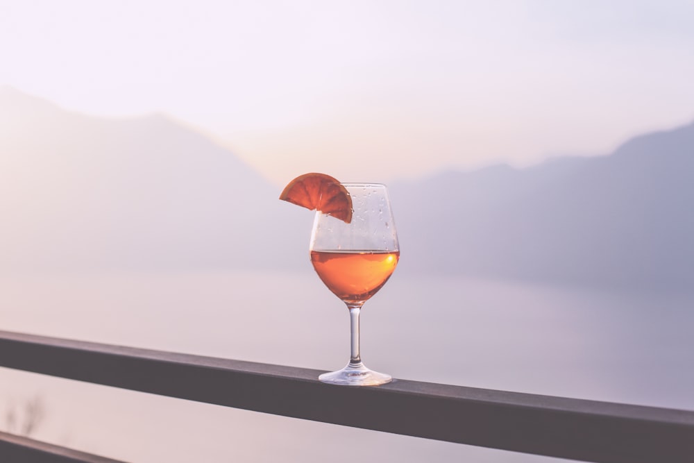 clear wine glass with brown liquid on table