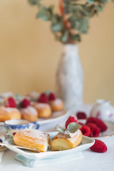Close-up of delicate Western pastries with powdered sugar and fresh berries on a white ceramic plate.