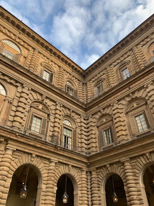 brown concrete building under blue sky and white clouds during daytime in Palazzo Pitti Italy