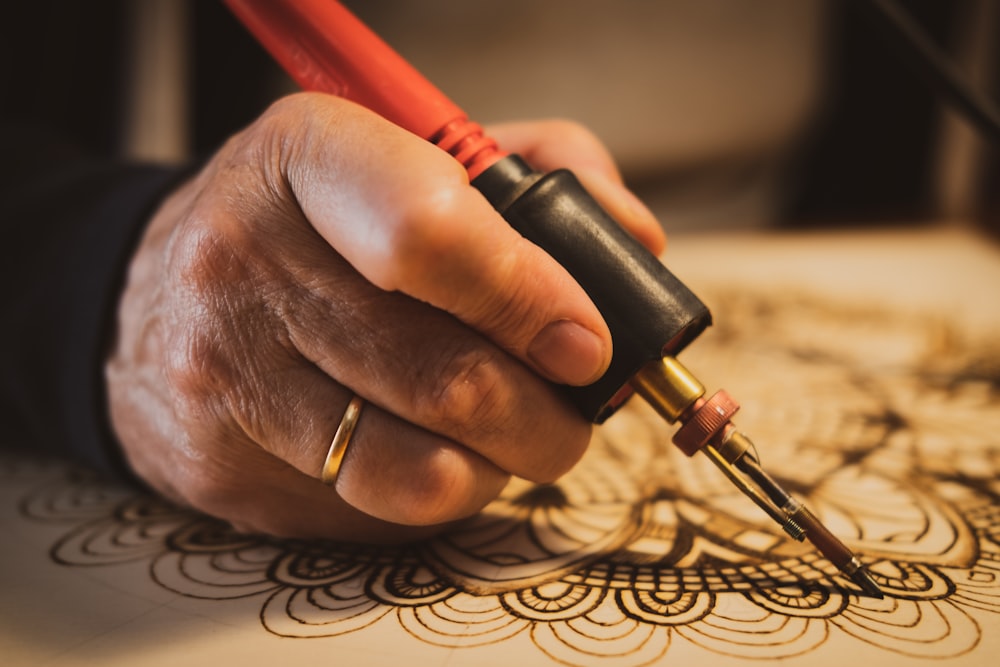 person holding red and black hand tool