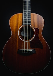 a close up of an acoustic guitar on a black background