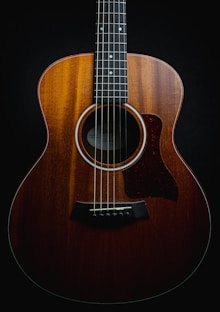 a close up of an acoustic guitar on a black background