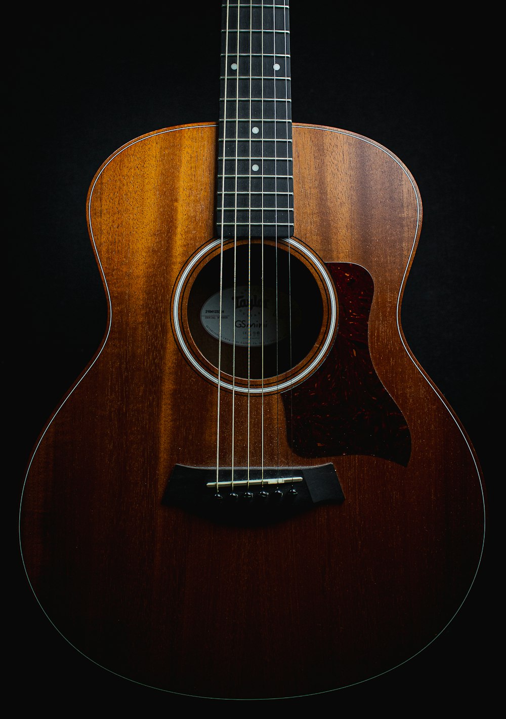 a close up of an acoustic guitar on a black background