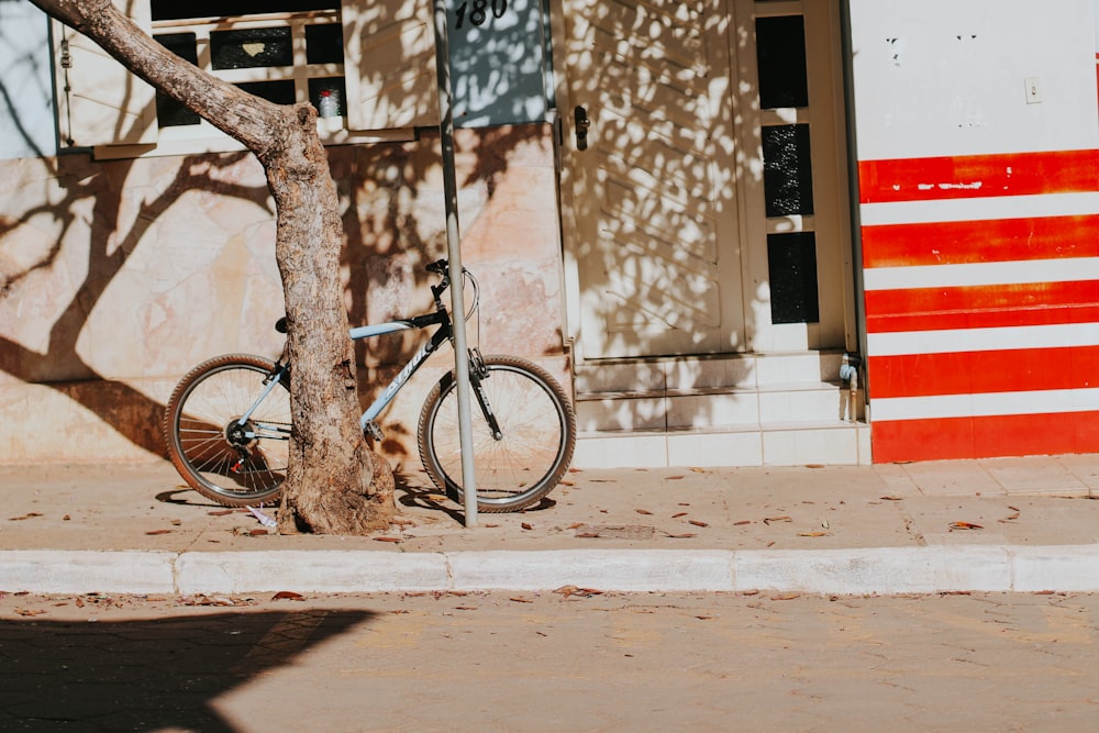 a bike parked next to a tree on a sidewalk