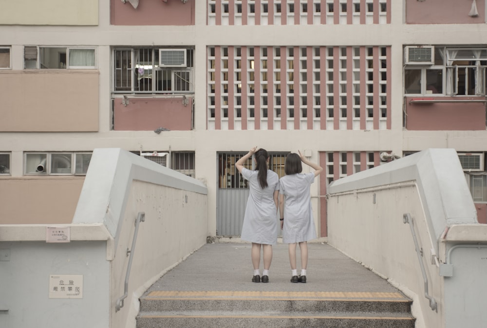 two people standing on a bridge in front of a building