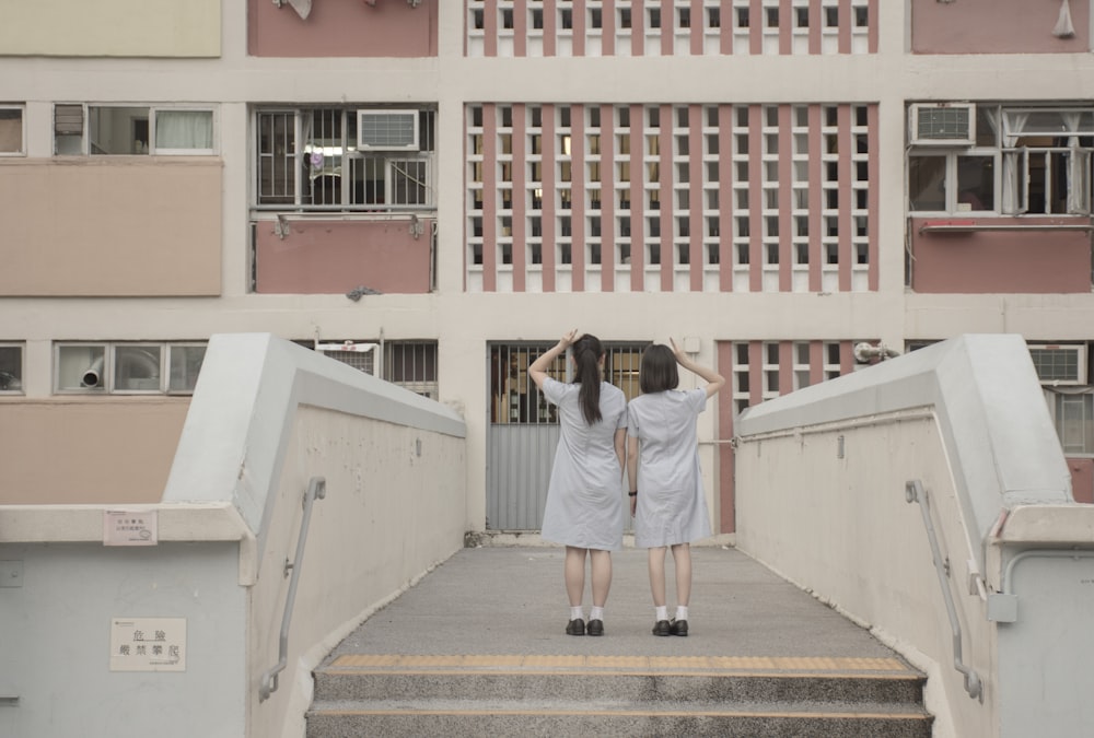 Dos personas de pie en un puente frente a un edificio