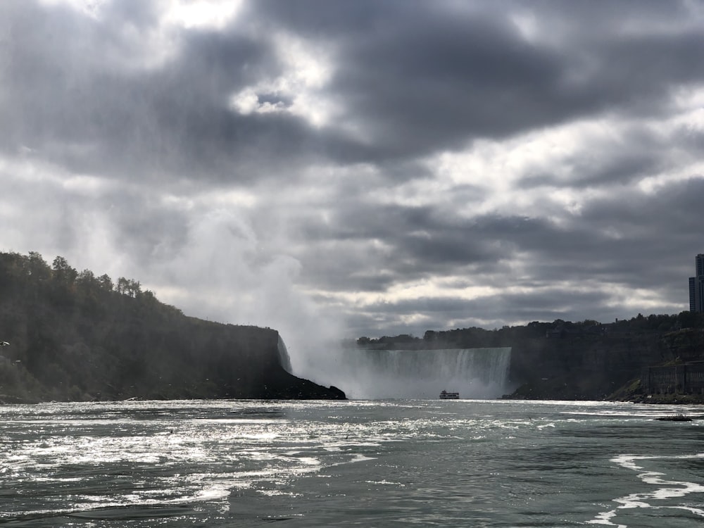 water falls under cloudy sky during daytime