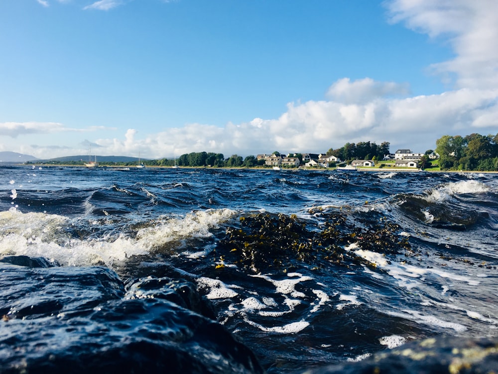 a body of water with waves and houses in the background