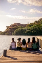 group of people sitting on brown wooden bench near body of water during daytime
