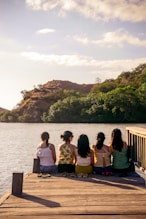 group of people sitting on brown wooden bench near body of water during daytime