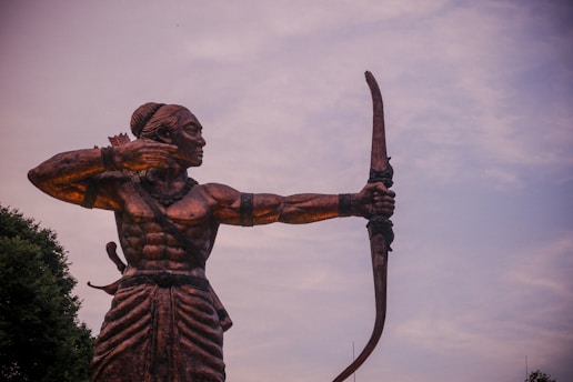 A skilled archer in traditional attire draws a bow atop a galloping horse under a clear sky.
