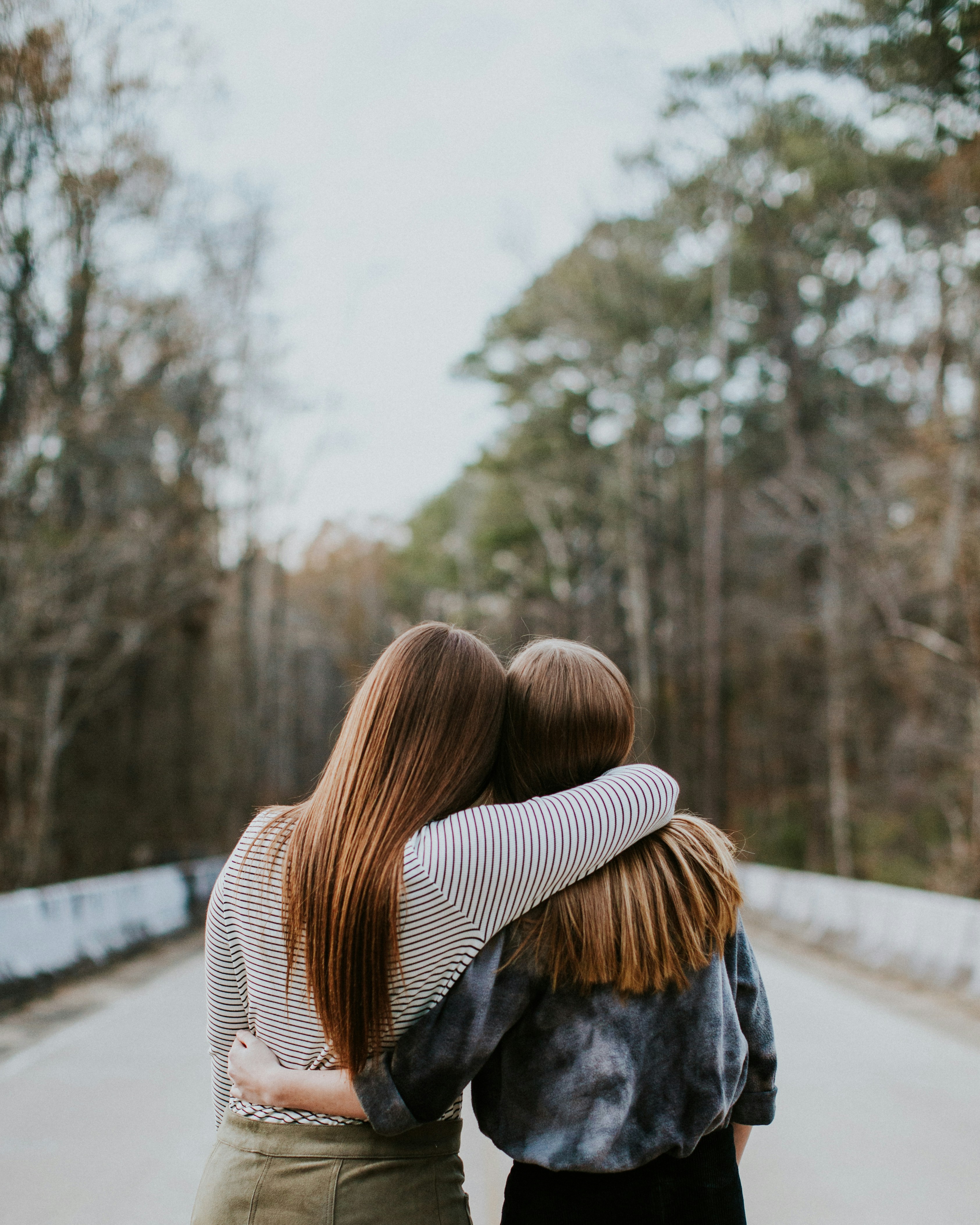 two girl best friends hugging each other facing opposite direction