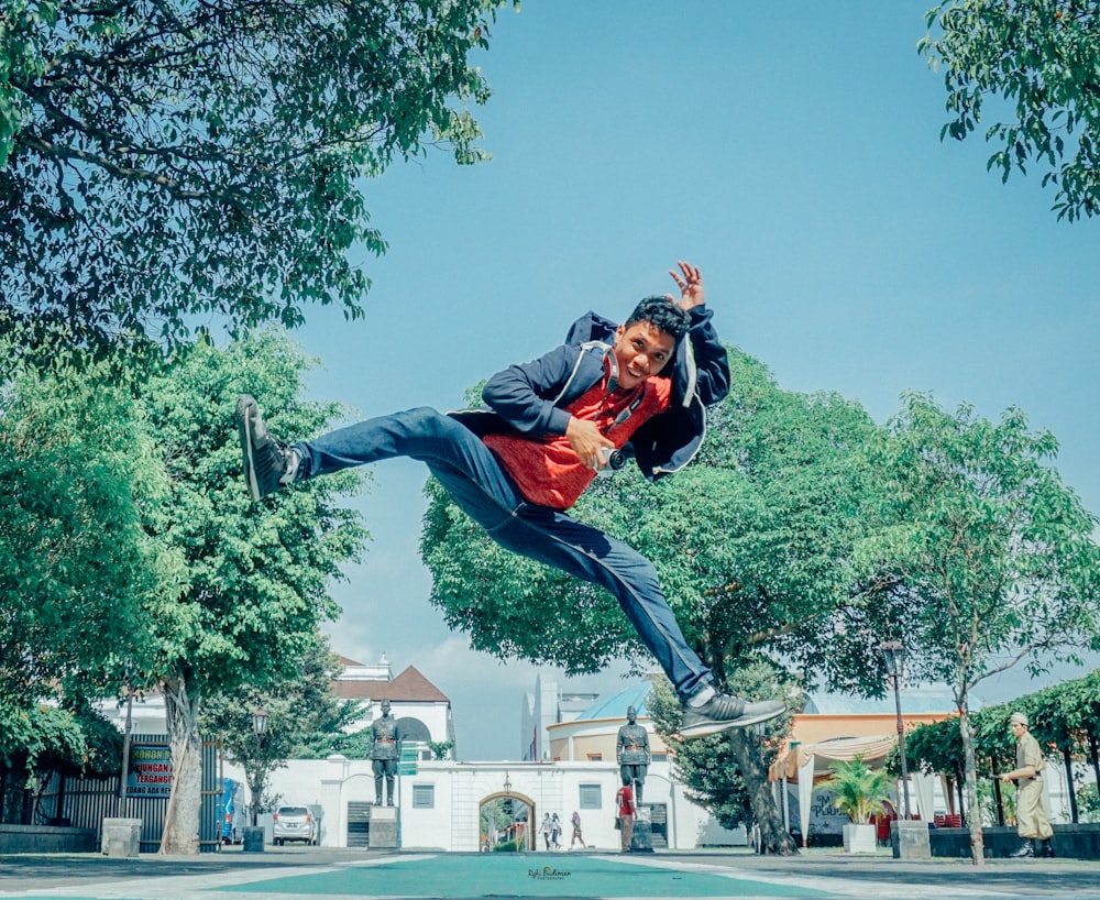 man in blue jacket and black pants jumping on mid air under blue sky during daytime